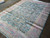 Angled view showing low even wool pile, blue floral field and faded rose border panels