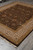 Brand new hand-knotted floral rug photographed at an angle on grey tile with gold borders