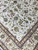 Design detail of olive palmettes, red blossoms and arabesque leaf scrollwork over ivory ground