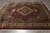 Hand-knotted wool and silk rug on grey tile showing scalloped medallion and dense fish pattern field