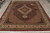 Burgundy and ivory Oriental rug angled view with cotton fringe, red selvedge and palmette border