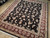 Angled showroom view of 8x10 hand-knotted wool rug with all-over floral vines and burgundy borders