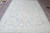 Soft powder blue area rug photographed lengthwise, central rosette medallion and sweeping ivory cartouches visible