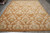 Hand-knotted European transitional rug laid flat showing symmetrical ivory floral repeat on warm gold ground