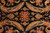 Detail of terracotta rosette and teal green leaf tips on jet black hand-knotted wool pile