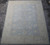 Angled floor view showing pale blue field, cream all-over florals and a wide ivory outer border