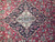 Close-up of navy lobed medallion with ivory center rosette on crimson flower-filled field