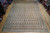 10'1" x 13'11" Persian paisley rug laid flat on showroom floor beside rolled inventory rugs