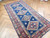 Angled view of antique Caucasian Kazak wool rug, linked diamond medallions and rosettes on navy