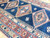 Close-up of hand-knotted wool pile showing rust medallion, latch hook edges and ivory arrow band