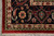 Corner close-up of the near black navy border, ivory guard band, green zigzag and cotton fringe