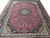 Floor-level view of rose red Persian rug with dense floral field and slate blue guard bands