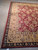 Corner of the 9x12 wool rug showing ivory fringe, black-navy border and gold palmette field