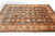 9x12 Indian wool rug viewed from the side, ivory border and serrated leaf vines visible