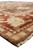Side profile of large wool area rug showing ivory fringe, rust border and brown field