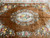 Golden brown field with floral garlands surrounding the oval medallion of this Aubusson design