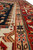 Border close-up showing peach guard stripe, teal rosettes and dense hand-knotted wool pile texture