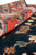 Rolled edge showing plush wool pile depth, rust border and deep navy field of the rug