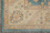 Woven corner of beige border with blue flowerheads, vine scrolls and aqua outer edge