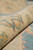 Rolled edge of the wool rug showing dense weave, short pile and beige backing