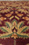 Low angle close up of gold and olive floral sprays repeating across the burgundy field