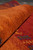 Rolled edge of the wool rug showing thick plush pile depth and rust orange band