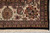 Corner close-up of ivory border with gold rosette, paisley motifs and clean cotton fringe