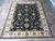 8' x 10'2" Jaipur Oriental rug displayed on travertine tile floor showing ivory border and black field