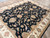 Angled view of black and ivory all over floral rug showing gold vine scroll and palmettes