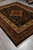 Full rug photographed at an angle on grey showroom tile, black ground and medallion centered