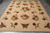 Hand-knotted modern rug photographed on grey tile showing borderless cream field and warm rust blossoms