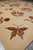 Large terracotta and olive butterfly motif woven in silk relief near the rug end