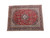 Angled full view of red and navy Persian Kashan rug showing ivory center medallion and floral borders