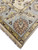 Corner of the Indian Oushak rug with cotton fringe, gold guard stripe, rust rosette