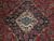 Close-up of ivory and blue medallion framed by graphite black floral cartouche on red field