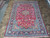 Formal 8x12 Persian area rug on tile, red ground, navy border, ivory fringe ends