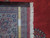 Back of this hand-knotted Persian rug with ruler showing knot count and authenticity tag