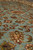 Low angle macro showing dense wool pile and crisp rust, gold and green floral drawing