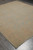 Transitional Afghan wool rug angled on grey floor, washed out green field with gold lattice