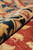 Rolled pile close-up showing wool luster, navy and gold border motifs over rust ground