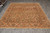 Hand-knotted Indian wool rug shown at an angle with ivory fringe and wide floral border