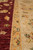 Ivory border meeting burgundy field, showing green leaf vines and orange guard stripe