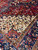 Ivory corner spandrel of angular vines meeting the rustic red field and navy main border