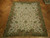 7'9 x 9'7 needlepoint flat weave rug displayed on herringbone parquet floor in showroom lighting