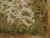 Corner detail of olive green border, leafy foliage and coral blossoms meeting the flat woven selvage