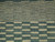Close-up of ivory dash pattern graduating across teal green hand-spun wool pile in modern design