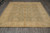 Light sage green and gold hand-knotted wool rug laid flat on grey tile showroom floor