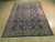 7x10 Persian Sarouk rug photographed from the side on pale wood flooring, borders fully visible