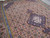 Pinkish brown Persian area rug photographed on floor, dense diamond lattice drawing across the open field