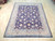 7' x 9' Persian Tabriz rug displayed on light wood floor showing navy field and ivory borders